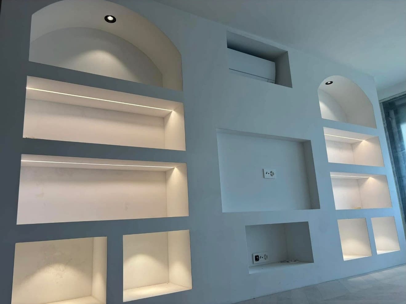 Mur de niches avec profilés LED intégrés et spots encastrés dans les arches