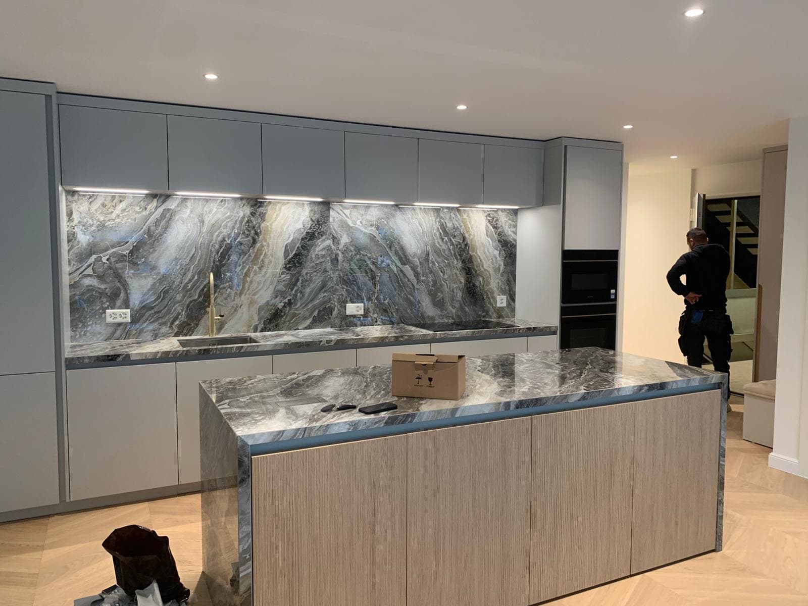 Cuisine moderne avec bandeau LED sous les meubles hauts, spots au plafond et prises intégrées à la crédence